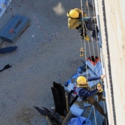 Håndværkere i gang med at udføre facadebeklædning på en bygning.
